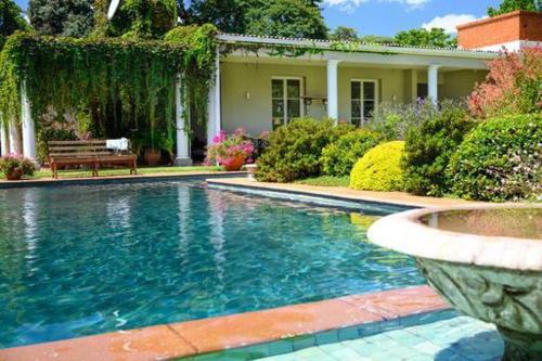 a swimming pool in front of a house at Chic studio nestled in lovely garden and pool-2254 in Harare
