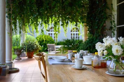 a wooden table with a vase of white flowers on it at Chic studio nestled in lovely garden and pool-2254 in Harare