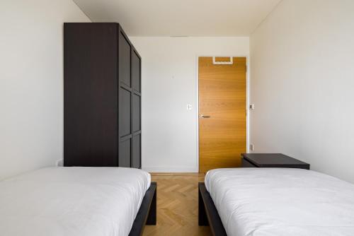 a bedroom with two beds and a black cabinet at Spacious, Modern 3-Bed Home in London