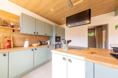 a kitchen with white cabinets and a flat screen tv at La Villa Wellness in Hastière-par-delà