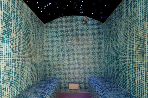 a room with two blue benches in a room with tiled walls at La Villa Wellness in Hastière-par-delà