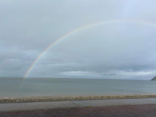 a rainbow in the sky over the ocean at Glan Y Mor Hotel (Adult Only) in Llandudno