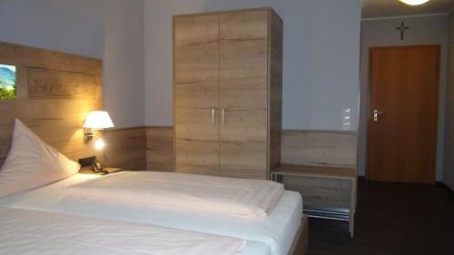 a bedroom with a white bed and a wooden cabinet at Hotel Bigger Hof - Wirtshaus Platzhirsch am Jahnplatz in Olsberg