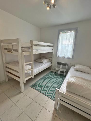 une chambre avec deux lits superposés et un tapis dans l'établissement Maison coeur de forêt, proche plage des Conches, à Longeville-sur-Mer