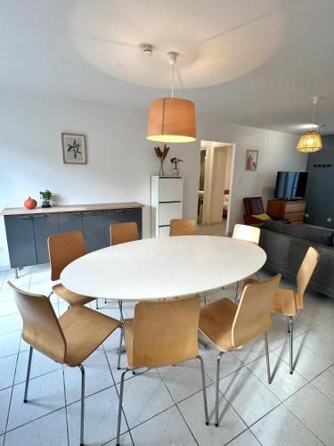 une salle à manger avec une table et des chaises blanches dans l'établissement Maison coeur de forêt, proche plage des Conches, à Longeville-sur-Mer