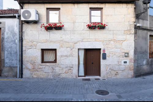 a stone building with flower boxes and a door at O Fogar da Pequena Galia in Caldas de Reis