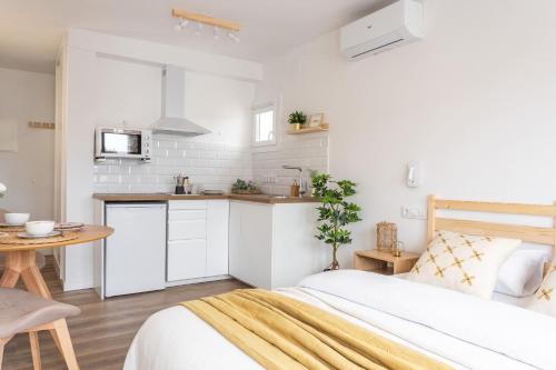 a white bedroom with a bed and a kitchen at Estudio Bianca in L'Escala