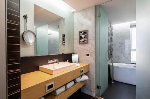 a bathroom with a sink and a mirror and a tub at ROMEO Napoli in Naples