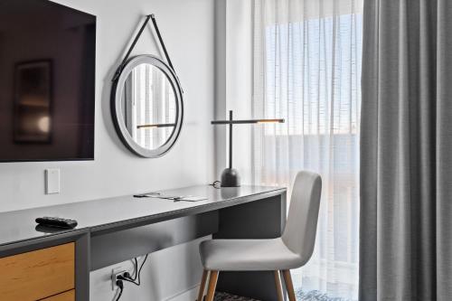 a desk with a chair and a mirror at DoubleTree by Hilton New York JFK Airport in Queens