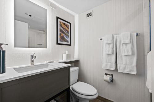 a white bathroom with a sink and a toilet at DoubleTree by Hilton New York JFK Airport in Queens