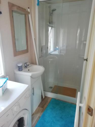 une salle de bain blanche avec une douche et un lavabo dans l'établissement Mobilhome 41m2 terrasse 15 m2, à Nissan-lez-Enserune