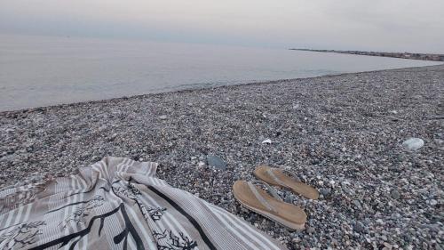 a pair of sandals sitting on a rocky beach at Focu e Mari in Mascali