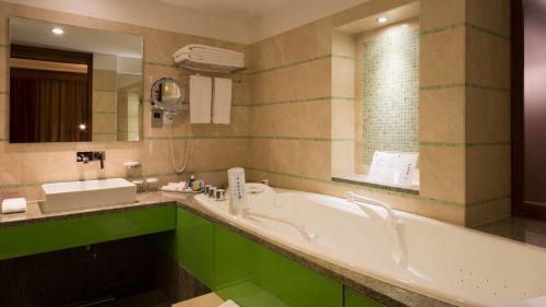a bathroom with a tub and a sink and a mirror at Holiday Inn Kuwait Al Thuraya City by IHG in Kuwait