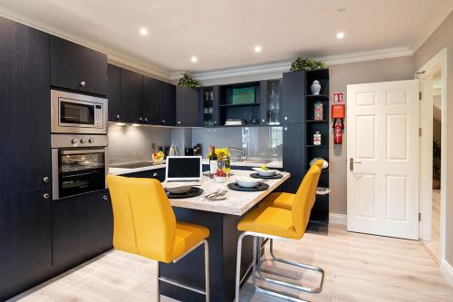 a kitchen with yellow chairs and a table with a laptop at Robeen House in Killarney