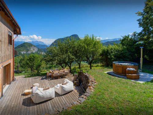 a deck with a table and chairs and a hot tub at La Ferme des Artistes - OVO Network in Mieussy
