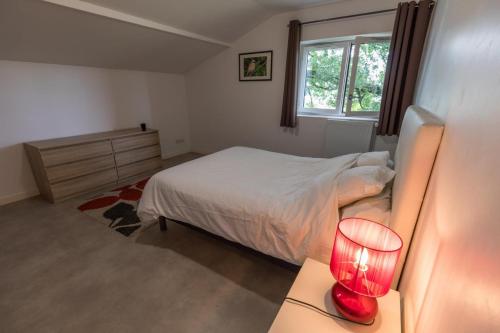 a bedroom with a bed and a red lamp on a desk at Gite les agreou in Arjuzanx