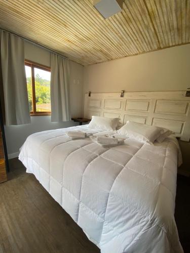 a large white bed in a bedroom with a window at Pousada Villa Manso in Conceição da Ibitipoca