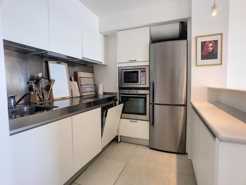 une cuisine avec des armoires blanches et un réfrigérateur en acier inoxydable dans l'établissement Très jolie vue mer et emplacement idéal - 243L RIV, à Cannes