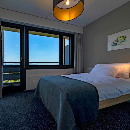a bedroom with a bed and two windows at Guggital Hotel Restaurant in Zug