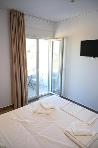 a bedroom with a white bed with a large window at Costa Varda Apartments in Mourteri