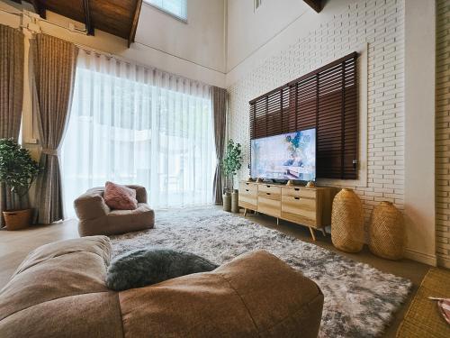 a living room with a couch and a flat screen tv at Le lanna villa at Center of old town with private pool in Chiang Mai