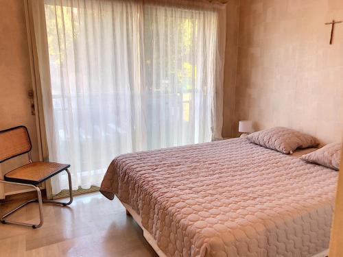 une chambre avec un lit, une chaise et une fenêtre dans l'établissement Terrasse vue mer, proche plages, piscine 258L TVLV, à Cannes