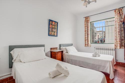 two beds in a room with a window at -Iponubahomes- Céntrica casa con jardín y chimenea in Baena