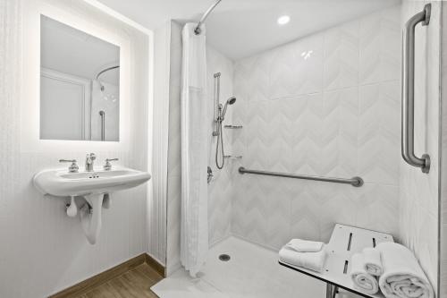a white bathroom with a sink and a shower at DoubleTree by Hilton New York JFK Airport in Queens