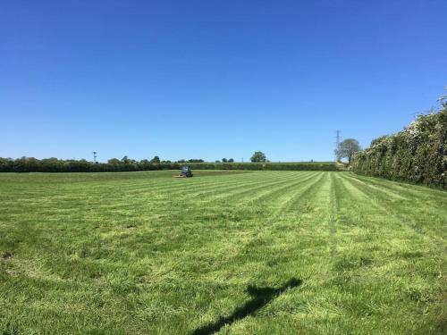 a large field with a tractor in it at Shepherds Haven in Draycott in the Moors