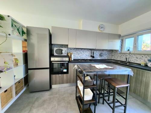 a kitchen with white cabinets and a island with bar stools at Villino Andromeda in Sèrapo