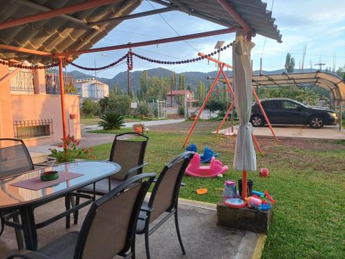a patio with a table and chairs and a playground at Villa Angela in Sikia