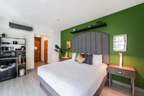 a bedroom with a large bed with a green wall at Claremont Hotel in Miami Beach