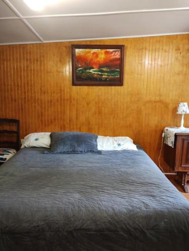 a bedroom with a bed and a painting on the wall at Cabaña en parcela a 5 minutos de Valdivia in Valdivia