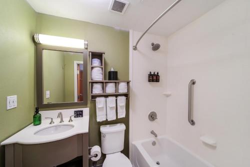 a bathroom with a sink and a toilet and a tub at Claremont Hotel in Miami Beach