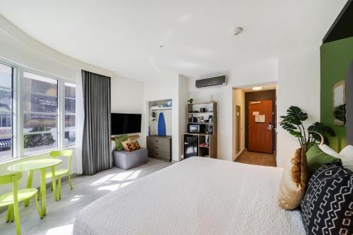 a bedroom with a white bed and a table and chairs at Claremont Hotel in Miami Beach