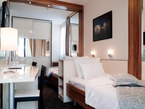 a hotel room with a bed and a table and a desk at Hotel Lighthouse in Igalo
