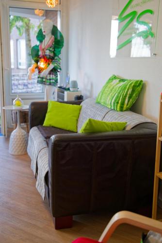 a living room with a brown couch with green pillows at Ferienwohnung Little Dragon - Rheinblick in Rees
