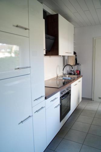 a white kitchen with white cabinets and a sink at Ferienwohnung Little Dragon - Rheinblick in Rees