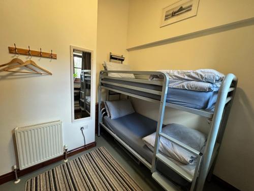 a room with two bunk beds and a mirror at Lands End Hostel and B&B in Sennen