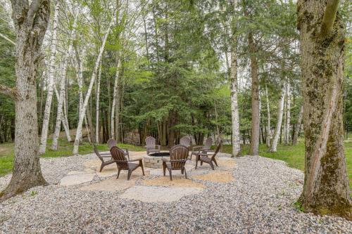 a group of chairs and a table in a forest at Waterfront Evart Getaway with Fire Pit on 82 Acres! in Evart