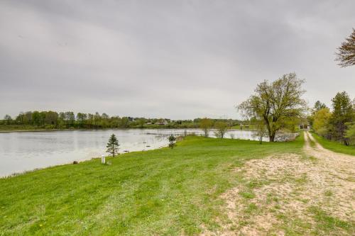 a grassy field next to a body of water at Waterfront Evart Getaway with Fire Pit on 82 Acres! in Evart