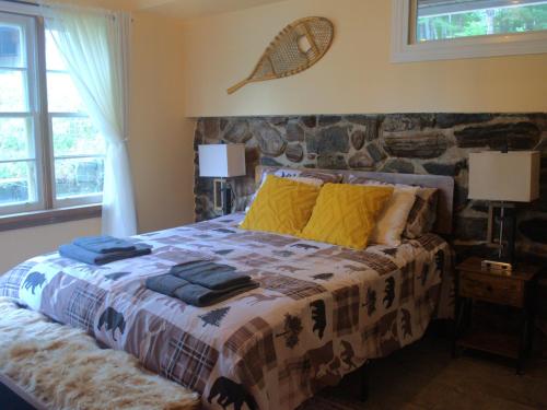une chambre avec un grand lit avec des oreillers jaunes dans l'établissement Escape to Corry Lake Cottage, à Chalk River
