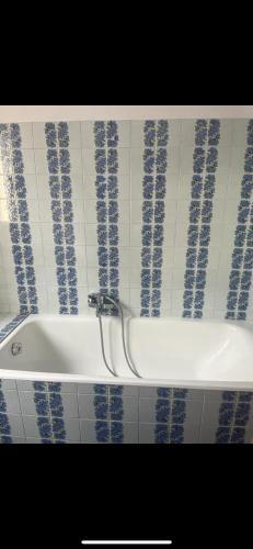 La salle de bains est pourvue d'une baignoire et de carrelage bleu et blanc. dans l'établissement Appartement chaleureux, à La Bollène-Vésubie