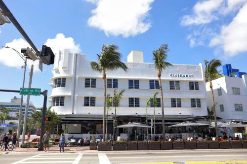 a white building with palm trees in front of it at Claremont Hotel in Miami Beach