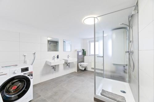a white bathroom with a washing machine and a sink at Perfekt für Firmen und Gruppen - 1 Haus, 2 XXL Wohnungen in Göppingen