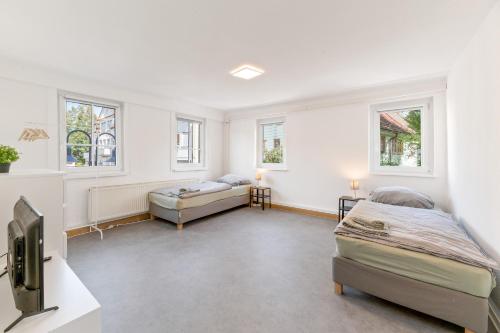 a bedroom with two beds and a tv and windows at Perfekt für Firmen und Gruppen - 1 Haus, 2 XXL Wohnungen in Göppingen