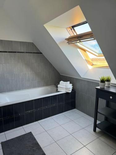 La salle de bains mansardée est pourvue d'une baignoire et d'une lucarne. dans l'établissement Maison Flair, à Varaville
