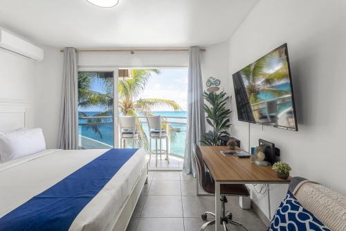 马霍礁Maho Beach House - Petite Studio - Ocean View的一间卧室设有一张床和一张书桌,享有海景