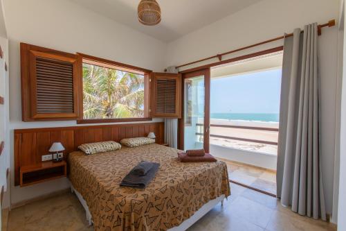Un dormitorio con una cama con vista al mar. en Villa Continentes Brasil & Maison de rêve sur la plage, en Guajirú