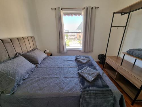 a bedroom with a bed with a blue comforter and a window at Apto 539 Teresópolis in Teresópolis